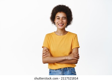 Cool And Confident Black Woman Winking, Smiling Assertive, Give A Wink, Standing Over White Background In Yellow T-shirt