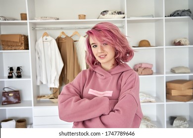 Cool Confident Stylish Hipster Gen Z Teen Girl Fashion Designer, Stylist With Pink Hair Piercing Wear Hoodie Looking At Camera Stand Arms Crossed In Front Of Modern Clothes Wardrobe Closet, Portrait.