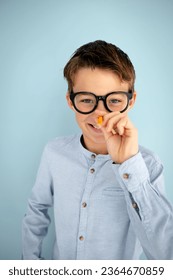 cool, cute young schoolboy with blue shirt, black glasses and pencil in front of blue background - Shutterstock ID 2364670859