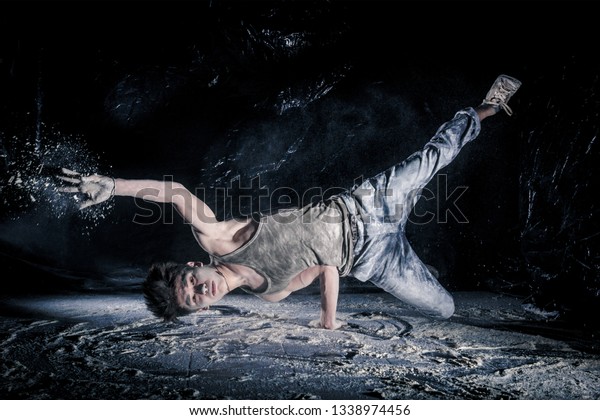 cool dirty\
сhinese  guy dancer in style of bboying doing complex tricks on\
floor in Studio filled with flour on black background. concept of\
space dance on surface of planet\
moon