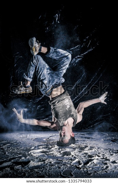 cool
dirty vietnamese  guy dancer in style of bboying doing complex
tricks on floor in Studio filled with flour on black background.
concept of space dance on surface of planet
moon