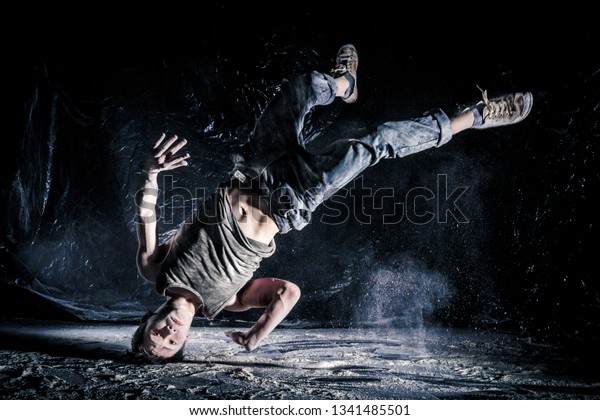 cool\
dirty vietnamese  guy dancer in style of bboying doing complex\
tricks on floor in Studio filled with flour on black background.\
concept of space dance on surface of planet\
moon