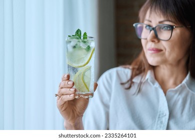 Cool drink mineral water with ice lemon mint leaves in woman's hand - Powered by Shutterstock