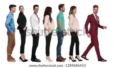 cool elegant man in burgundy suit is walking out of a line of people, on white background