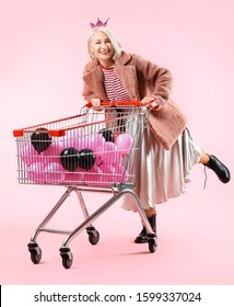 Cool Fashionable Mature Woman With Air Balloons In Shopping Cart On Color Background