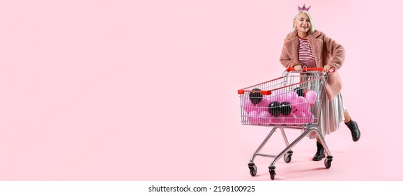 Cool Fashionable Mature Woman With Balloons In Shopping Cart On Pink Background With Space For Text