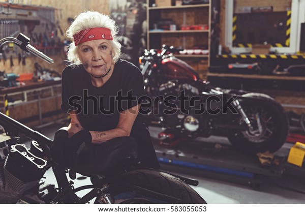 Cool female retiree locating next to motorcycle