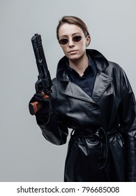 Cool Female Spy Agent In Black Leather Coat, She Is Holding A Gun And Posing