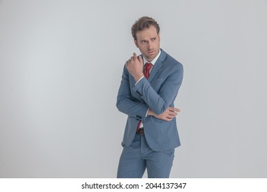 Cool Frowning Man In Blue Suit Folding Arms, Looking To Side And Being Confident In Front Of Gray Background In Studio, Posing