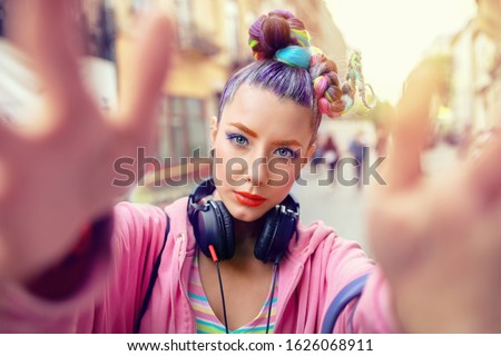 Cool funky young rebel girl with headphones and crazy hair enjoy power of music taking selfie on street – hipster woman with trendy avant-garde look having fun - Music fan concept with carefree teen