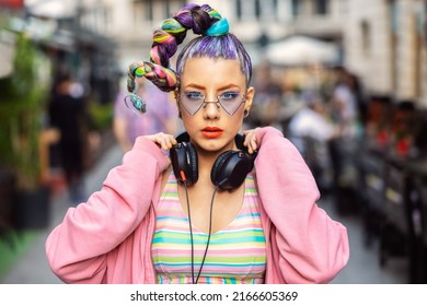 Cool funky young woman with trendy eyeglasses listening music on headphones outdoor - Shutterstock ID 2166605369