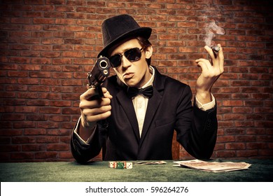 Cool Gangster mit einem Haufen Geld bedroht Waffe. Glücksspielindustrie, Casino. Underworld Konzept. 