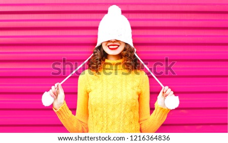 Cool girl wearing a colorful knitted yellow sweater over pink background