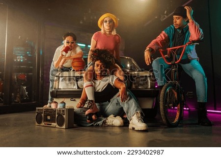 A cool group of retro stylish friends are hanging out outdoors with their bike, car, boombox and roller skates.