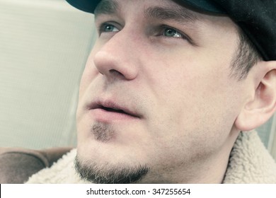 Cool Guy In Aviator Jacket And Newsie Cap Relaxes Against A Glass Wall