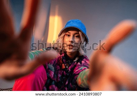 Cool hipster student woman wearing stylish outfit looking at camera and correcting her hat