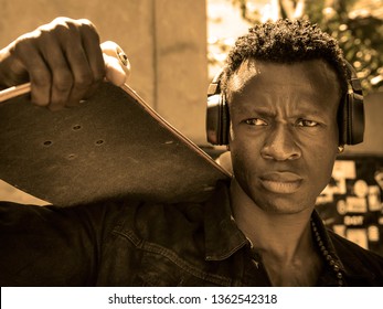 Cool Isolated Portrait Of Young Attractive And Confident Hipster Black African American Man Walking On Street Holding Skate Board Looking A Badass Guy In Urban Style Concept