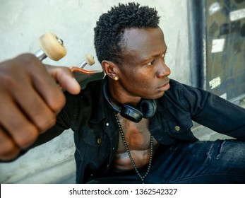 Cool Isolated Portrait Of Young Attractive And Confident Hipster Black African American Man Leaning On Street Wall Holding Skate Board As Badass Guy In Urban Style Concept