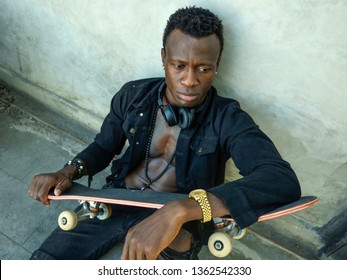 Cool Isolated Portrait Of Young Attractive And Confident Hipster Black African American Man Leaning On Street Wall Holding Skate Board As Badass Guy In Urban Style Concept