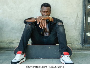 Cool Isolated Portrait Of Young Attractive And Confident Hipster Black African American Man Leaning On Street Wall Holding Skate Board As Badass Guy In Urban Style Concept