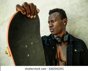 Cool Isolated Portrait Of Young Attractive And Confident Hipster Black African American Man Leaning On Street Wall Holding Skate Board As Badass Guy In Urban Style Concept