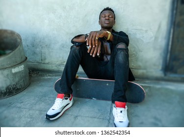 Cool Isolated Portrait Of Young Attractive And Confident Hipster Black African American Man Leaning On Street Wall Holding Skate Board As Badass Guy In Urban Style Concept