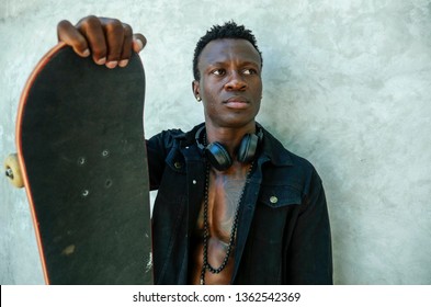 Cool Isolated Portrait Of Young Attractive And Confident Hipster Black African American Man Leaning On Street Wall Holding Skate Board As Badass Guy In Urban Style Concept