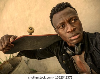 Cool Isolated Portrait Of Young Attractive And Confident Hipster Black Afro American Man Leaning On Street Wall Holding Skate Board As Badass Guy In Urban Style Concept