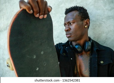 Cool Isolated Portrait Of Young Attractive And Confident Hipster Black Afro American Man Leaning On Street Wall Holding Skate Board As Badass Guy In Urban Style Concept