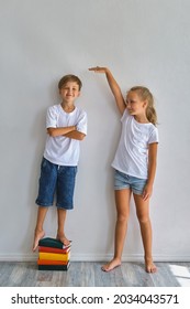 Cool Kids, Little Boy And Girl Measure Their Height And Compare, Have Fun Near White Wall