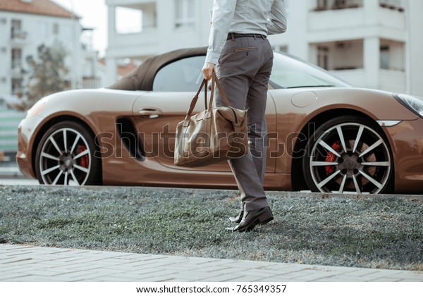 Cool\
man beautiful model outdoors, city style fashion. A handsome man\
model walking in the city center next to some cars. urban setting.\
The young boy as trendy, modern clothing with\
bag