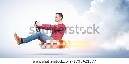 Cool man in casual clothes holds a steering wheel in his hands while driving an alternative rocket vehicle, on blue background.