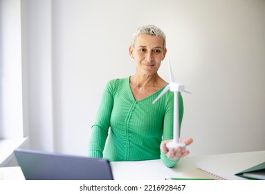 Cool Middle-aged Scientist With Short Hair Holds Model Of Wind Turbine In Her Hands