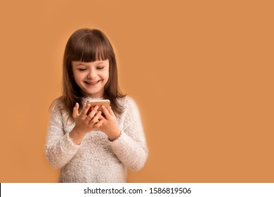 Cool Modern Game For Kids, Girl Playing Phone Online Using Internet Technologies, Creative Children, Happy Expression On Face. Funny And Joyful. Creative Modern Kid