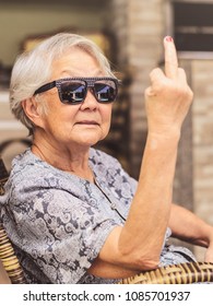 Cool Old Lady, Wearing Sunglasses, Expressing Herself Showing The Middle Finger.