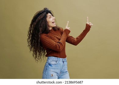  COOL PURPOSE FOR YOU. Curly Latin Female Say Oh Wow, Look Up And Show Copy Space For Your Advertisement. Autumn Winter Collection Clothing Fashion Brands. Studio Shoot With Green Olive Background. 