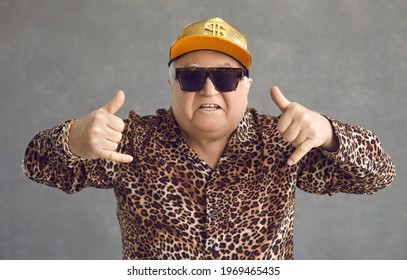 Cool Retired Gangsta Granddad Flexing To Rap Music. Portrait Of Funny Weird Active Rich Senior Man In Baseball Cap, Trendy Eyeglasses And Leopard Patterned Party Shirt Posing And Having Fun In Studio