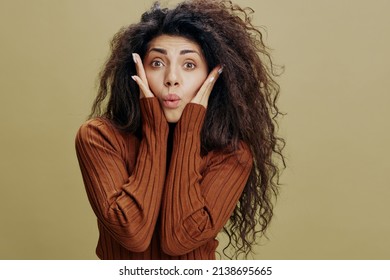 COOL SALE OFFER. Shocked Curly Latin Woman Look At Camera, Touch Cheek And Say Wow. Copy Space For Fashion Brands Accessories And Clothing, Free Place For Ad. Studio Shoot Isolated Green Background