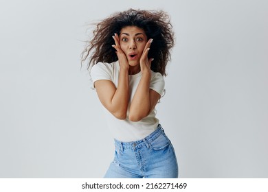 COOL SALE OFFER. Shocked Curly Latin Woman Look At Camera, Touch Cheek And Say Wow. Copy Space For Fashion Brands Accessories And Clothing, Free Place For Ad. Studio Shoot Isolated White Background