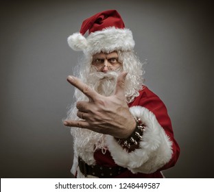 Cool Santa Claus Making An Heavy-metal Gesture And Staring At Camera: Rock Christmas Concept