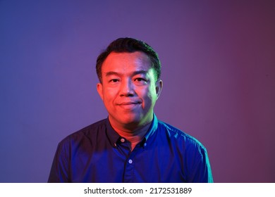 The Cool Senior Asian Man On The Blue Background Under The Color Gel Lighting. 