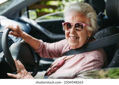 Cool senior woman in sunglasses driving car alone, enjoying car ride. Safe driving for elderly adults, older driver safety. - Powered by Shutterstock