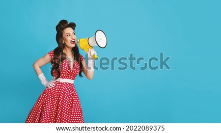 Cool shopping offer. Millennial pinup woman in retro outfit making announcement, shouting into megaphone on blue studio background, banner with free space. Huge sale, promotion, advertisement