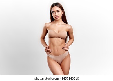 Cool Slim Model In Fashion Lingerie Boasting About Her Flat Stomach, Slim Waist. Close Up Photo. Isolated White Background. Studio Shot