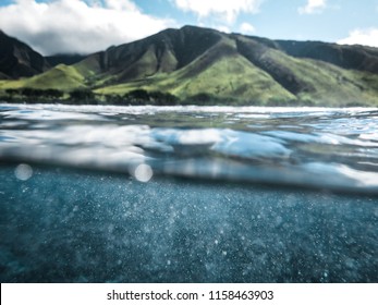 Cool Split Photo Half Underwater with Clear Blue Ocean Water Drops and Lush Green Mountain Background with Sunshine on Clear Beautiful Day in Tropical Island Paradise on Maui Hawaii