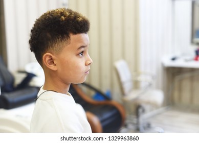 Cool stylish fashion mixed boy  in hair salon studio. Fashion kids. Curly hair african american boy close up portrait.