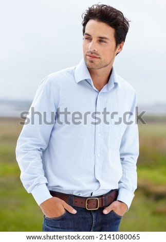 Cool and stylish. A handsome young model standing outside with his hands in his pockets.