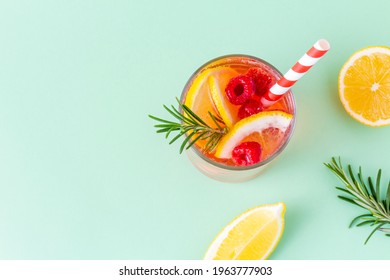 Cool summer drink with lemon, raspberry and rosemary in glass with striped eco straw on green background. Bright cold fruit cocktail, top view with copy space. - Shutterstock ID 1963777903