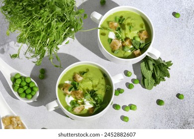 Cool Summer Pea Soup with Croutons, Sour Cream, Fresh Mint, Pea Sprouts, and Parsley Green Oil. Vegetarian Cuisine Idea. Artisanal Photography, Not AI - Powered by Shutterstock