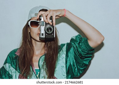 Cool teenager. Fashionable girl in colorful trendy jacket and vintage retro sunglasses with camera film in 80s - 90s style. Teenage girl at the disco, on a white background. - Shutterstock ID 2174662681